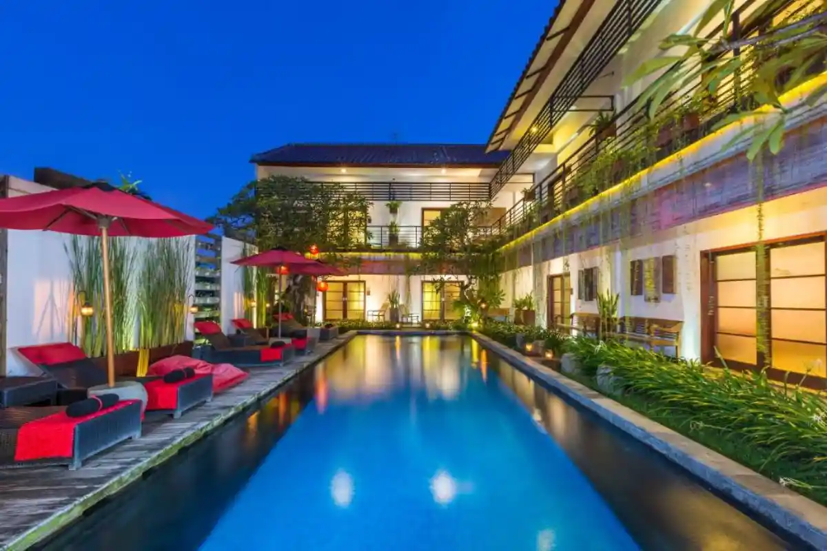 illuminated boutique hotel pool courtyard at night with loungers